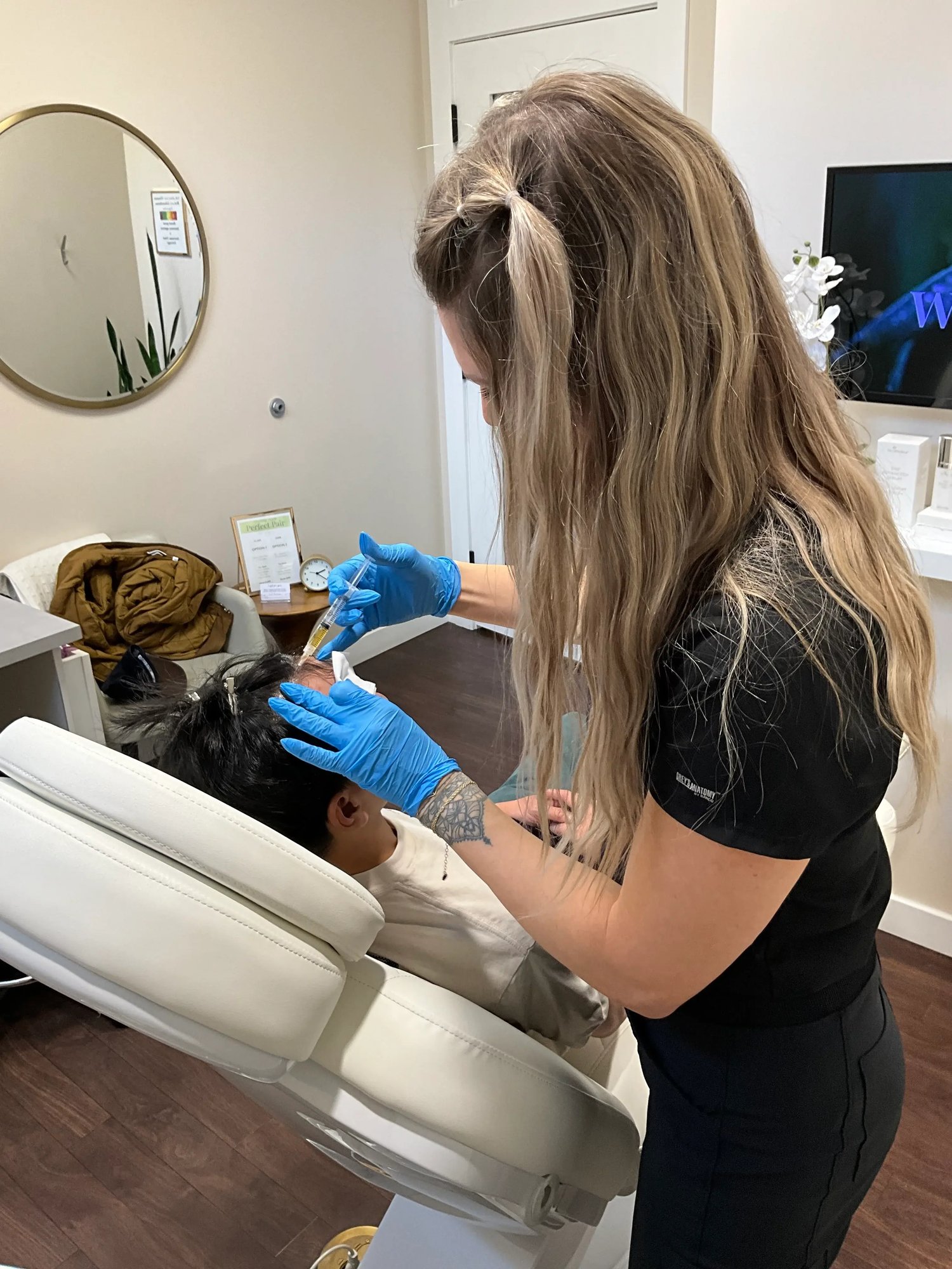 provider-with-long-blonde-hair-injecting-a-patient’s-scalp-while-wearing-blue-gloves-in-a-clinic-setting-as-part-of-prp-saskatoon-treatment